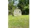Outdoor storage shed in backyard with painted door and window, surrounded by grass at 6335 Linden Dr, Indianapolis, IN 46227
