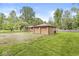Two-car detached garage with additional lean-to storage, set in a grassy yard with mature trees at 6401 N Oakland Ave, Indianapolis, IN 46220