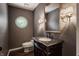 Elegant powder room featuring a unique round window, ornate mirror, and stylish vanity with granite countertop at 7770 N Pennsylvania St, Indianapolis, IN 46240