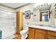 This bathroom includes a walk-in shower, wood-look floors, and vanity with framed mirror at 8145 Bentley Farms Dr, Indianapolis, IN 46259