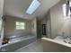 Bathroom featuring a skylight, soaking tub, and a separate shower with a glass door at 8507 Promontory Rd, Indianapolis, IN 46236