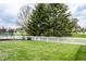 A well-maintained backyard features a white picket fence, lush lawn, and a trampoline for outdoor enjoyment at 941 Pine Ridge Way, Brownsburg, IN 46112