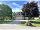 Well-maintained brick house with a three-car garage, mature trees, and a sunny sky above at 941 W Barouche, Pendleton, IN 46064