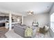 Open concept living room with modern gray sofa, ceiling fan, and adjacent kitchen with breakfast bar at 991 Terra Ln, Franklin, IN 46131