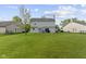 Spacious backyard with lush green grass, view of the home's exterior and the neighborhood surroundings at 10616 Bartley Dr, Indianapolis, IN 46236