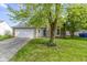 Inviting single-story home with a well-kept lawn, a two-car garage, and mature trees in the front yard at 10616 Bartley Dr, Indianapolis, IN 46236