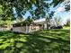 Home exterior surrounded by lush green lawn, mature trees, and partial driveway view at 10751 N Kitchen Rd, Mooresville, IN 46158