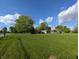 Charming home with a sprawling green lawn, mature trees, and a lovely facade under a beautiful blue sky at 10751 N Kitchen Rd, Mooresville, IN 46158