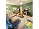 Green living room featuring a ceiling fan, sofa, decorative rug, and fireplace at 10946 Maze Rd, Indianapolis, IN 46259