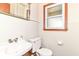 Bathroom featuring a white sink, toilet, and mirror over a sink with a window, and laminate trim at 11603 Peacock Dr, Indianapolis, IN 46236