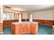 Kitchen island with wood cabinets, laminate countertops, and green carpeting, surrounded by a wood paneled wall at 11603 Peacock Dr, Indianapolis, IN 46236