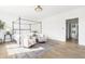 A bright bedroom featuring a four-poster bed, seating area, hardwood floors, and large windows at 11904 Spring Mill Rd, Carmel, IN 46032