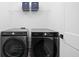 Modern laundry room featuring a Samsung washer and dryer, with overhead storage, maximizing functionality at 127 Monon Green Blvd, Carmel, IN 46032