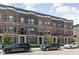 Street view of attractive brick townhomes featuring multiple stories, detailed trim, and convenient front parking at 127 Monon Green Blvd, Carmel, IN 46032