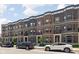 Street view of three-story brick townhomes with gray trim, private balconies and easy street parking at 127 Monon Green Blvd, Carmel, IN 46032
