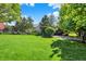 Scenic backyard with green grass, trees, landscaping, a black metal fence, and playground equipment in view at 13827 Driftwood Dr, Carmel, IN 46033