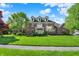 Stately brick home featuring dormer windows and a manicured lawn with mature trees at 13827 Driftwood Dr, Carmel, IN 46033