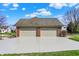 A three-car garage featuring brick accents and a pristine driveway, with lush greenery at 13827 Driftwood Dr, Carmel, IN 46033