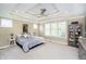 Spacious bedroom with decorative tray ceiling, neutral carpet, and ample natural light from large windows at 14003 Grannan Ln, Carmel, IN 46074