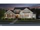 Beautiful two-story home with a stone and brick facade, manicured lawn, and professional landscaping at twilight at 14003 Grannan Ln, Carmel, IN 46074
