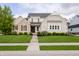 Charming two-story home with stone and brick, complemented by a lush green lawn and inviting walkway at 14003 Grannan Ln, Carmel, IN 46074