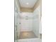Modern walk-in shower with glass door, white tiled walls, and mosaic accent stripe at 14003 Grannan Ln, Carmel, IN 46074