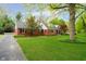 Charming brick home featuring manicured lawn, mature trees, black shutters, and dormer windows at 1409 Alimingo Dr, Indianapolis, IN 46260
