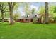Brick home boasts mature trees, green lawn, dormer windows, and a welcoming front entrance at 1409 Alimingo Dr, Indianapolis, IN 46260