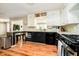 Kitchen featuring black and white cabinets, black appliances, and wood flooring at 1409 Alimingo Dr, Indianapolis, IN 46260