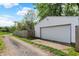 Exterior view of a detached garage with white siding and a large door, accessible by a gravel driveway at 1421 Laurel St, Indianapolis, IN 46203