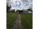 Charming home with a red door and inviting front porch sits on a large, grassy lot under a dramatic sky at 1503 E 20Th St, Muncie, IN 47302
