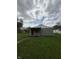 Modest home with gray siding, a red door, and a covered porch sits on a spacious lawn under a cloudy sky at 1503 E 20Th St, Muncie, IN 47302