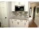 Kitchenette with white cabinetry, black hardware, mosaic backsplash and granite countertops at 15203 Shoreway Ct, Carmel, IN 46032