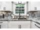 Close up of kitchen area with granite counters, black hardware, and black and white backsplash at 15203 Shoreway Ct, Carmel, IN 46032
