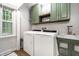 Well-lit laundry room with green cabinets, utility sink, and modern washer and dryer at 15203 Shoreway Ct, Carmel, IN 46032