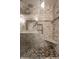 The luxurious shower has stone-look tiled walls, a pebble floor, a glass door, and a built-in bench at 15203 Shoreway Ct, Carmel, IN 46032
