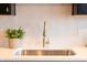 Detail of a modern kitchen sink featuring a gold faucet, white countertops, and herringbone backsplash at 1525 Marlowe Ave, Indianapolis, IN 46201