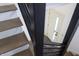 Modern staircase featuring hardwood treads, white risers, and black metal railings and a view of a door at 1525 Marlowe Ave, Indianapolis, IN 46201