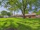 Expansive backyard with mature trees, manicured lawn, storage shed and partial view of brick home with screened porch at 1813 Kingsley Dr, Anderson, IN 46011