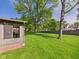 Lush, well-maintained lawn in a spacious backyard with mature trees and partial view of the screened porch at 1813 Kingsley Dr, Anderson, IN 46011