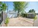 View of detached garage with carport and concrete driveway, surrounded by mature trees and privacy fence at 1932 Central Ave, Columbus, IN 47201