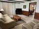 Living room with wood paneled accent walls and plush seating area is open to the dining room at 2927 E 8Th St, Anderson, IN 46012