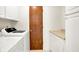 Bright laundry area with modern white appliances, storage cabinets, and a wooden door at 374 S Baldwin St, Bargersville, IN 46106