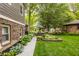 Landscaped backyard featuring a brick house with a pathway, patio set, and garden at 411 Woodland W Dr, Greenfield, IN 46140