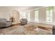 Living room featuring hardwood floors, bright windows, stylish houndstooth chairs, and a decorative area rug at 411 Woodland W Dr, Greenfield, IN 46140