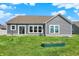 View of the backyard, showcasing the siding, windows and well-maintained lawn with a small garden at 49 Manchester Dr, Trafalgar, IN 46181