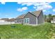 Beautiful backyard view of home with green grass, garden plot, and well-maintained gray siding at 49 Manchester Dr, Trafalgar, IN 46181