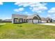 Charming single-story home with a gray exterior, stone accents, and a well-manicured lawn on a sunny day at 49 Manchester Dr, Trafalgar, IN 46181