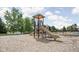 Community playground with a tan slide on a wood chip base, next to pool area, under a partly cloudy sky at 4956 Waterside Cir, Carmel, IN 46033