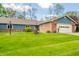 Charming single-story home with a well-manicured lawn, attached garage, and a mix of brick and blue siding at 618 N Buckingham Ct, Anderson, IN 46013